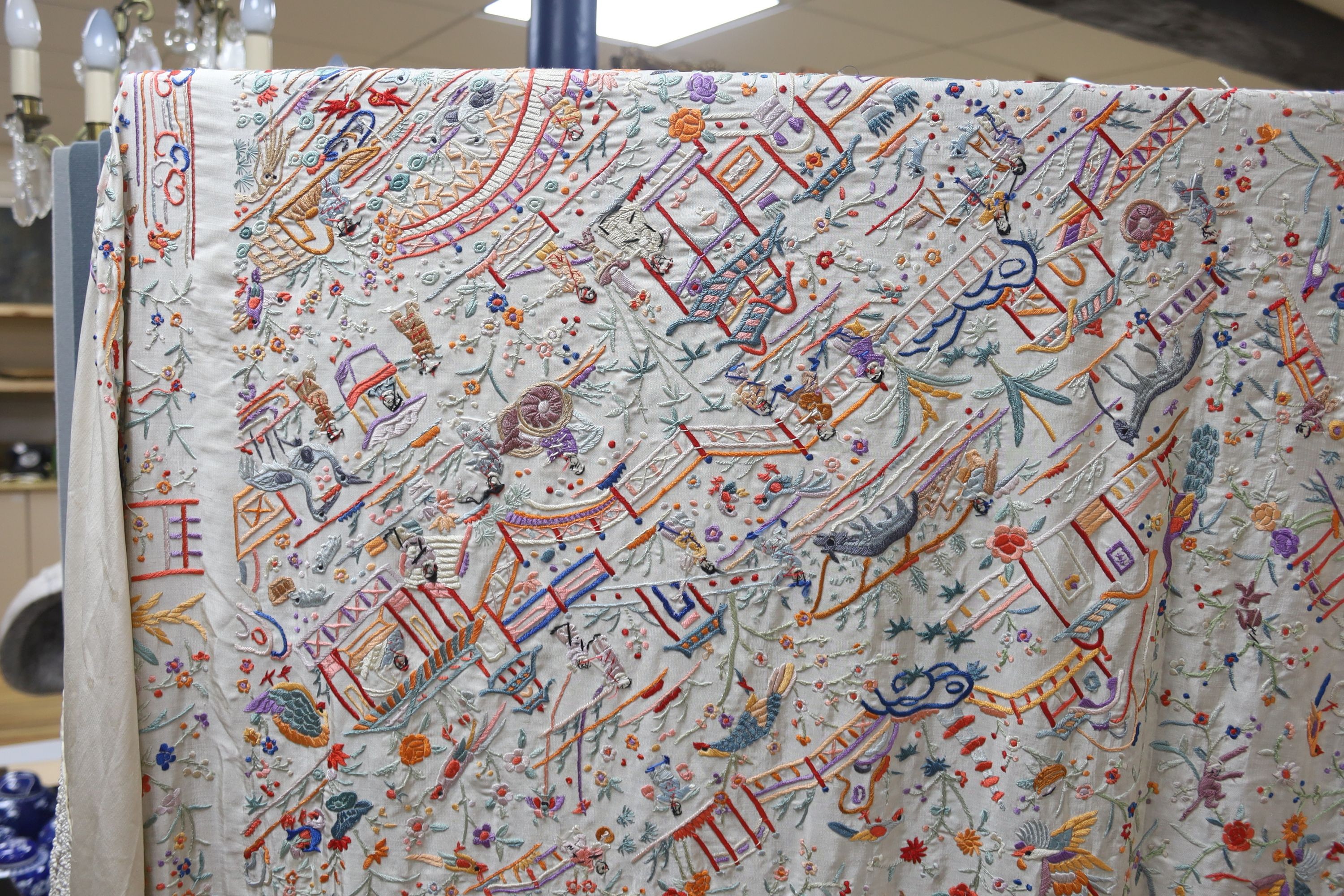 A Chinese cream silk shawl with fine multi coloured all over embroidery depicting figurative scenes and animals